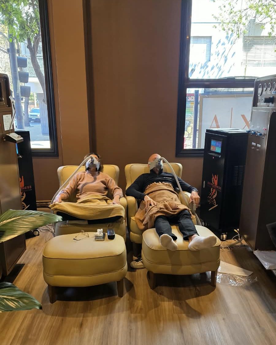 Sesión de IHHT en Biowellness: dos personas recostadas en sillones junto a la ventana, con la mascarilla de hipoxia-hiperoxia puesta