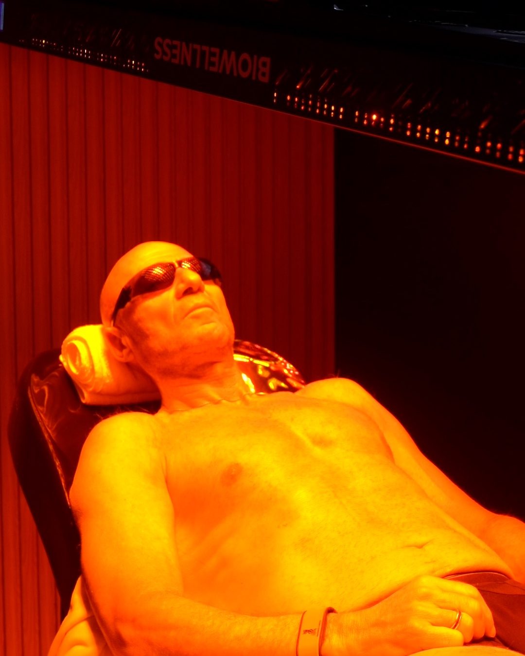 Sesión de Red Light full body en Biowellness: un hombre recostado bajo el panel de luz roja, con anteojos de protección